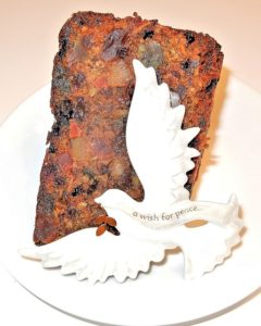 Slice of Christmas cake with paper dove.