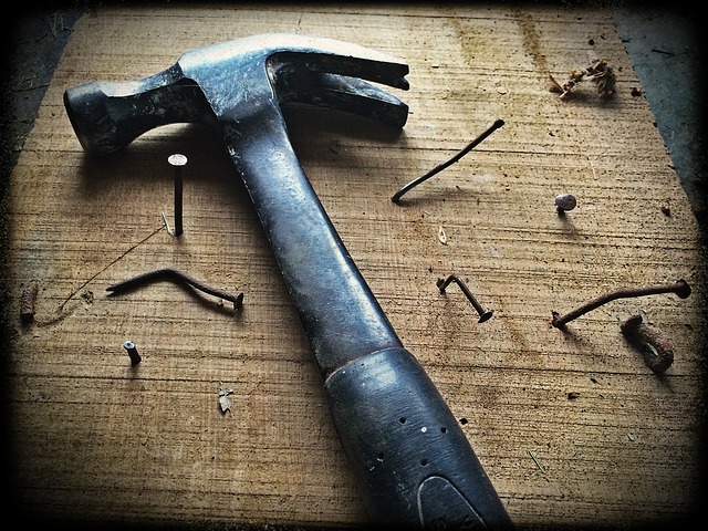 Hammer laid on wood surrounded by bent nails