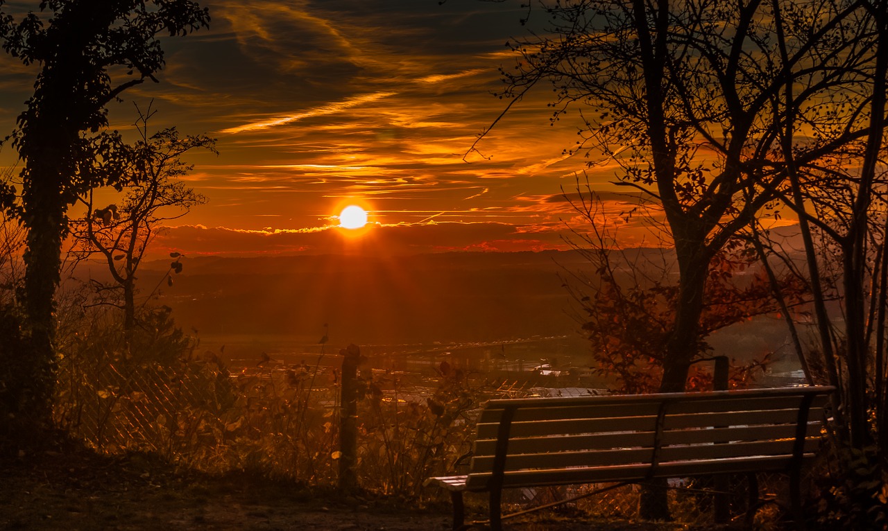 sunset over a town, bench in foreground