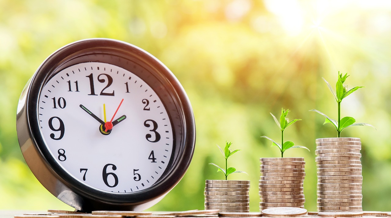 Clock face, stacks of coins with green shoots