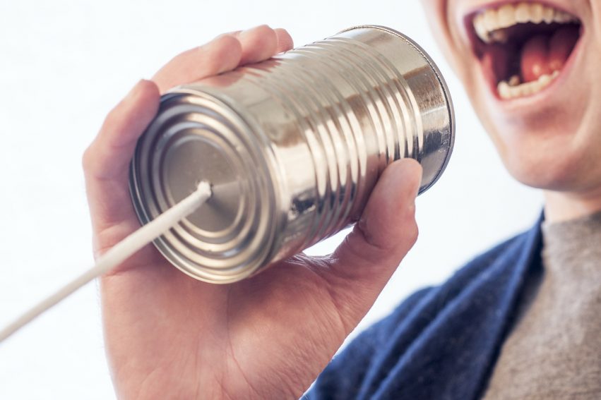 man speaking into tin can microphone